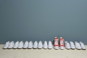 A red pair on Converse stands out in a line of plain white shoes