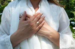 Woman wearing white with her hands over her heart